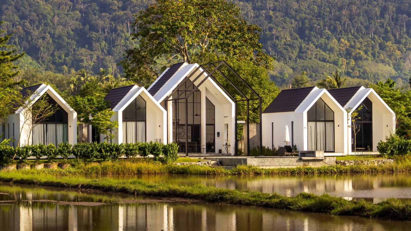 Ezu Isle's row of white A-frame villas at golden hour, reflected in the flooded padi field in front