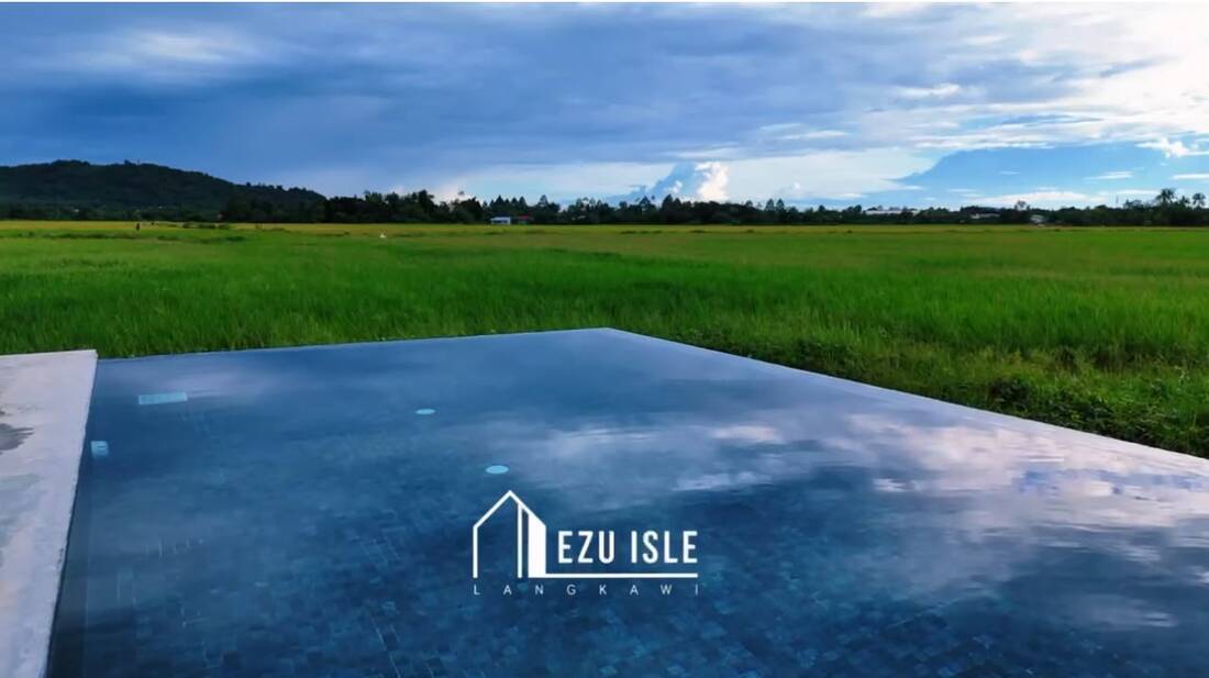 Infinity pool edge dissolving into the green padi fields, hills on the horizon